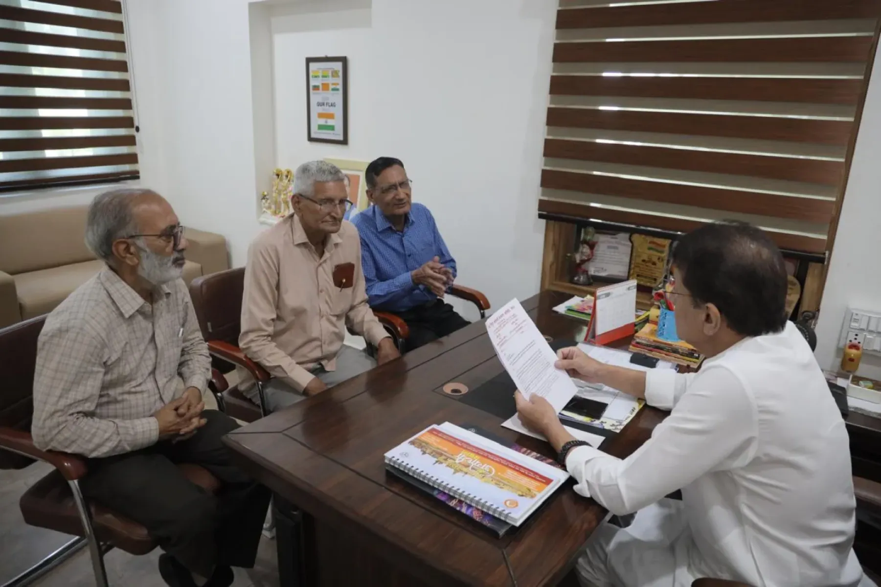 Retired officials discuss health center move and distribute Ramayan copies house-to-house.